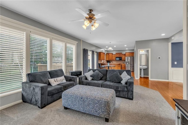 living area with recessed lighting, a ceiling fan, baseboards, and light wood finished floors