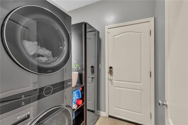 clothes washing area with laundry area, stacked washer and dryer, and light tile patterned flooring