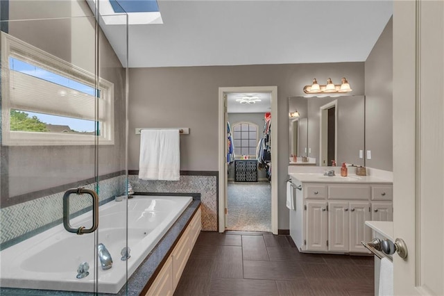 full bathroom with a tub with jets, a shower with shower door, a skylight, and vanity