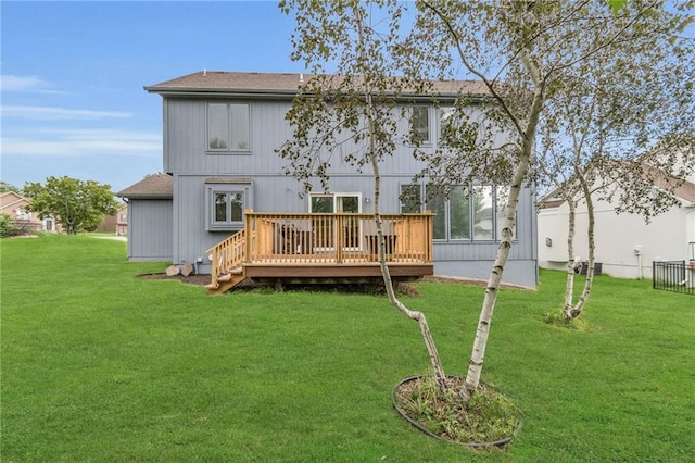 back of house with a shingled roof, a yard, and a deck
