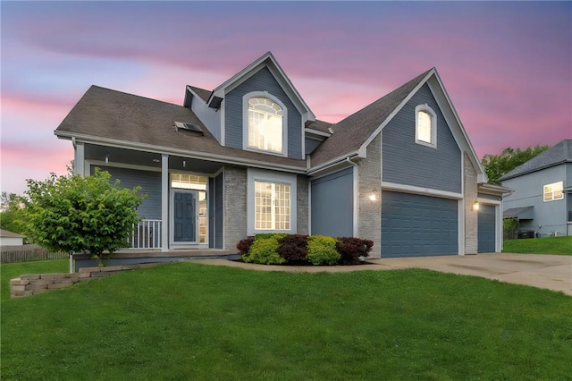 traditional home with a porch, driveway, a lawn, brick siding, and an attached garage
