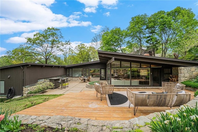 back of property featuring a deck, stone siding, and a chimney