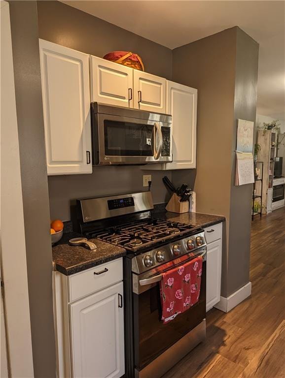 312 Kickapoo St, Hiawatha, KS 66434 - kitchen featuring dark stone counters, wood finished floors, white cabinetry, and appliances with stainless steel finishes