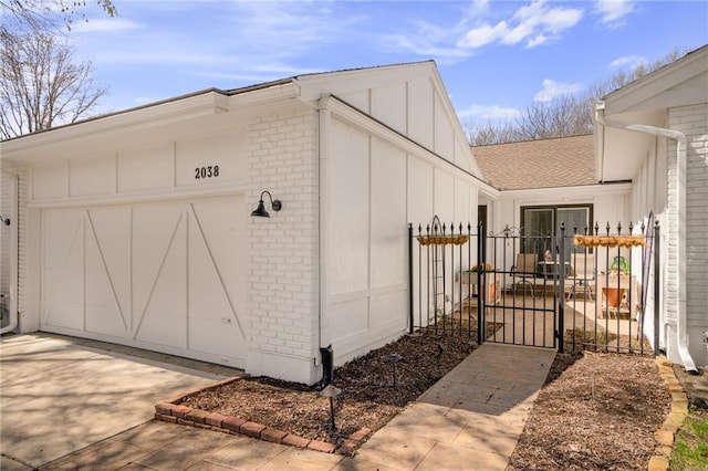 view of outdoor structure with a garage, fence, driveway, and a gate