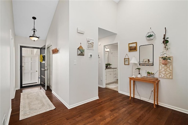 foyer with a high ceiling, baseboards, and dark wood finished floors