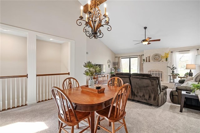 dining area featuring a brick fireplace, light colored carpet, vaulted ceiling, and ceiling fan with notable chandelier