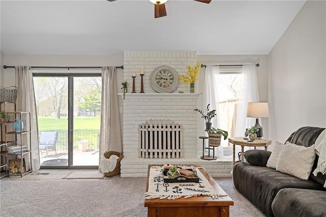 carpeted living room with a ceiling fan, vaulted ceiling, a brick fireplace, and a healthy amount of sunlight