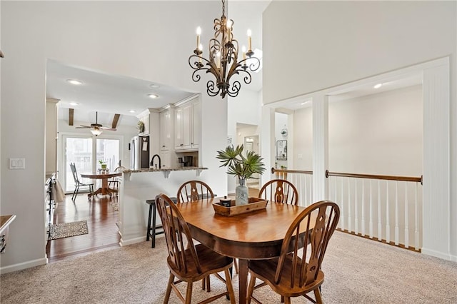 carpeted dining area with recessed lighting, a towering ceiling, ceiling fan with notable chandelier, and baseboards