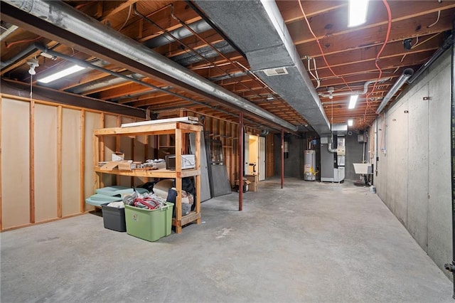 unfinished below grade area featuring water heater, a sink, and heating unit