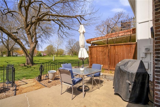 view of patio with fence, outdoor dining area, and a grill