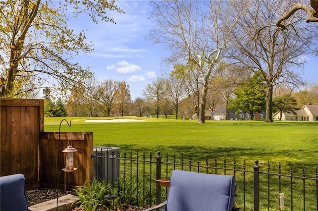 view of yard featuring central AC unit, fence, and view of golf course