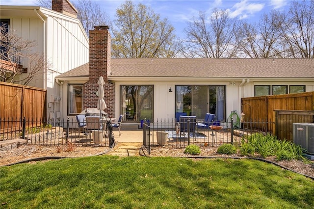 rear view of property with a patio, a chimney, central AC unit, and a lawn