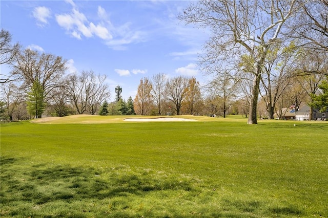 surrounding community with golf course view and a yard