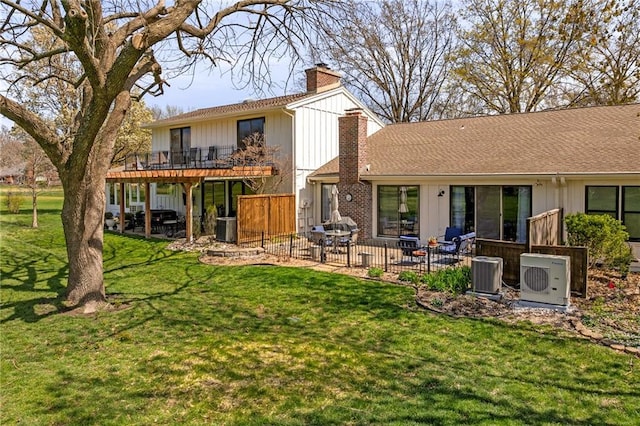 back of property with a patio area, cooling unit, a lawn, and a chimney