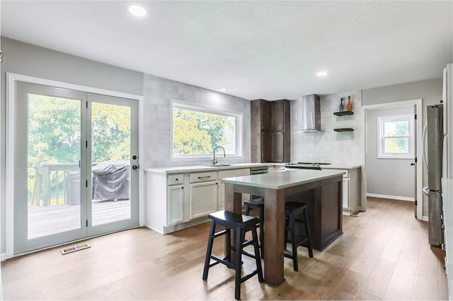 222 Chippewa Ln, Lake Winnebago, MO 64034 - kitchen featuring wall chimney exhaust hood, tasteful backsplash, light wood-type flooring, light countertops, and appliances with stainless steel finishes