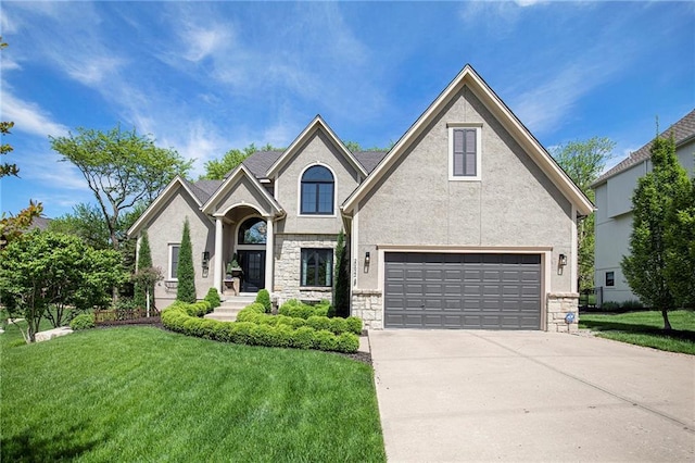 french country inspired facade featuring stucco siding, concrete driveway, a front lawn, and stone siding