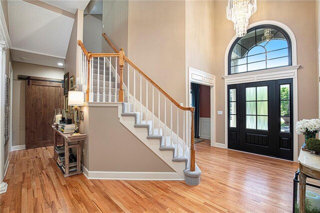 entryway with high vaulted ceiling, a chandelier, wood finished floors, and stairway