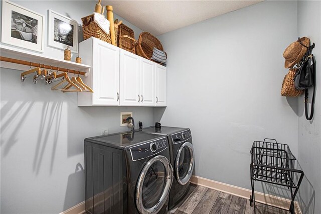 laundry area featuring cabinet space, separate washer and dryer, baseboards, and dark wood finished floors