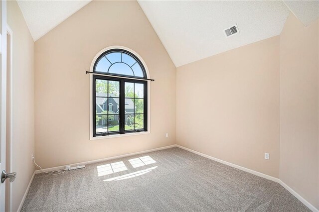 carpeted empty room with visible vents, baseboards, and high vaulted ceiling