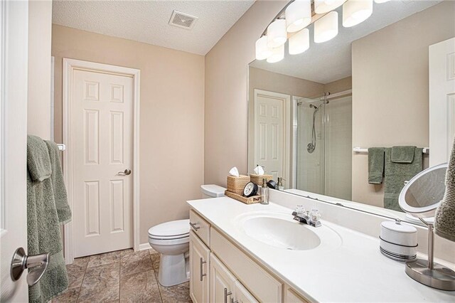 bathroom with vanity, toilet, baseboards, a shower stall, and visible vents