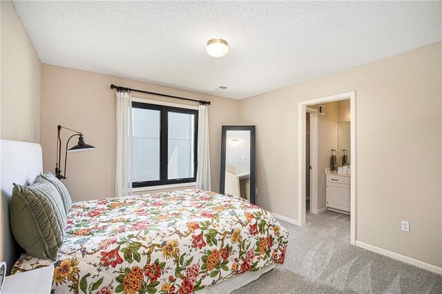 bedroom featuring baseboards, connected bathroom, a textured ceiling, and light colored carpet