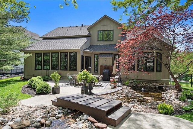 rear view of property featuring fence, a patio, and a shingled roof