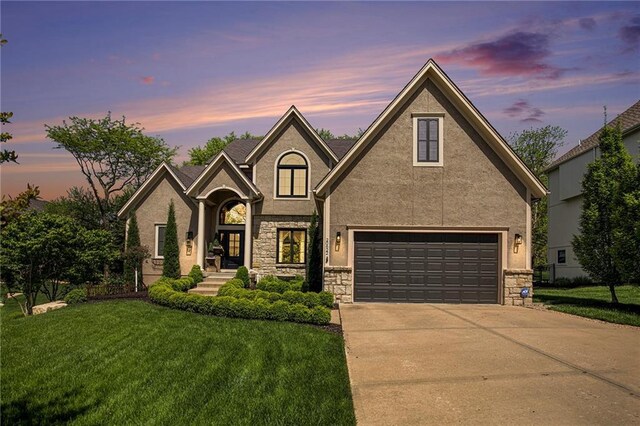 traditional-style home featuring a front yard, driveway, stone siding, and stucco siding