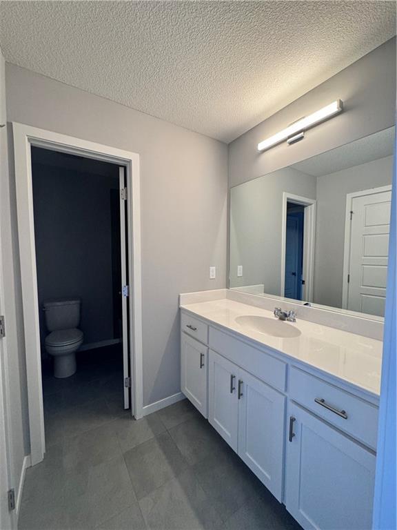 11432 S Langley St, Olathe, KS 66061 - bathroom with toilet, a textured ceiling, vanity, and baseboards