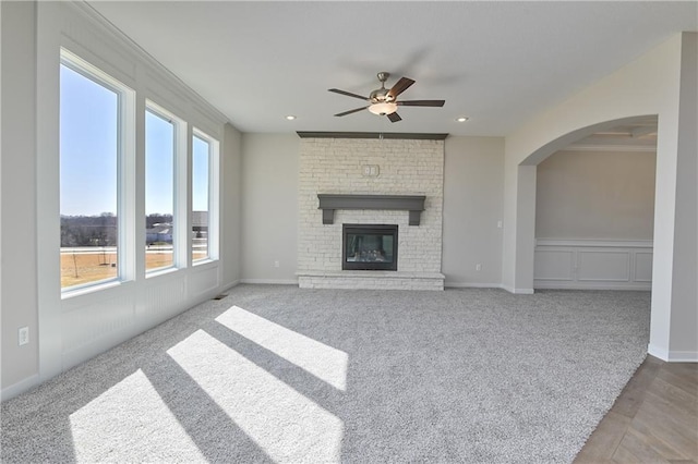 11448 S Langley St, Olathe, KS 66061 - unfurnished living room with a fireplace, arched walkways, ceiling fan, and carpet
