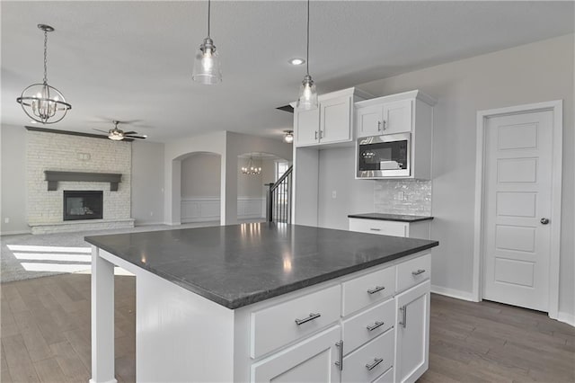 11448 S Langley St, Olathe, KS 66061 - kitchen featuring built in microwave, white cabinets, arched walkways, dark wood finished floors, and ceiling fan with notable chandelier