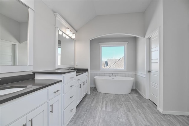 11448 S Langley St, Olathe, KS 66061 - bathroom featuring vanity, wainscoting, wood finished floors, a soaking tub, and vaulted ceiling