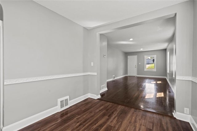 empty room with wood finished floors, baseboards, and visible vents