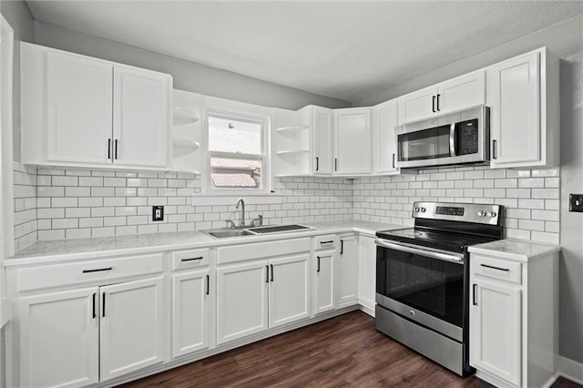 kitchen with white cabinets, open shelves, a sink, dark wood finished floors, and stainless steel appliances