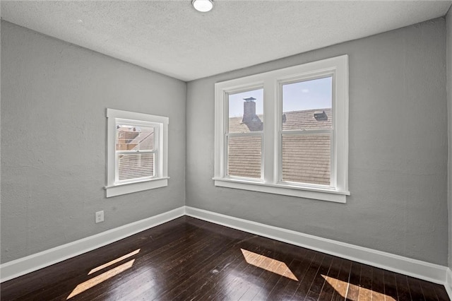 unfurnished room with a textured wall, dark wood-style flooring, baseboards, and a textured ceiling