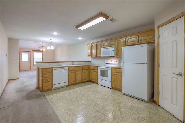 kitchen with visible vents, a sink, light countertops, a peninsula, and white appliances