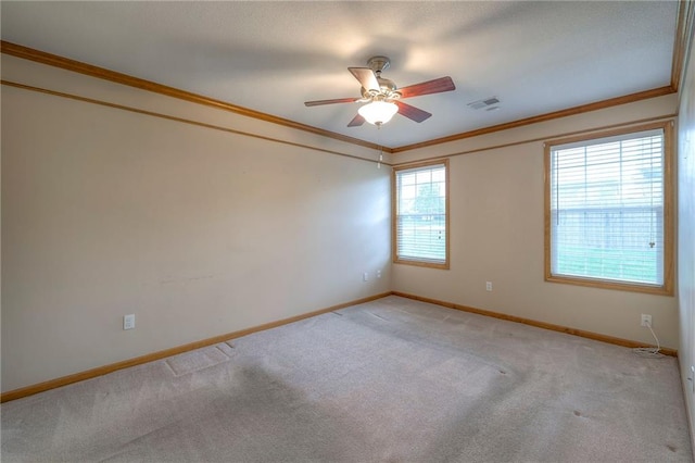 spare room with visible vents, ornamental molding, carpet, and ceiling fan