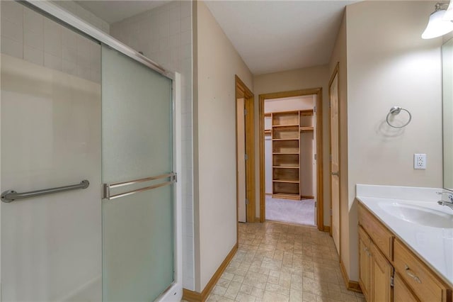 bathroom featuring baseboards, a spacious closet, and a stall shower