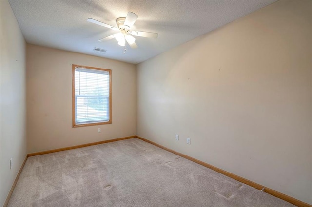 empty room featuring a ceiling fan, a textured ceiling, visible vents, baseboards, and carpet flooring