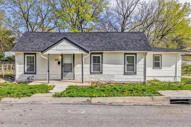 2130 E 83rd St, Kansas City, MO 64132 - view of front facade featuring fence, stone siding, and a shingled roof