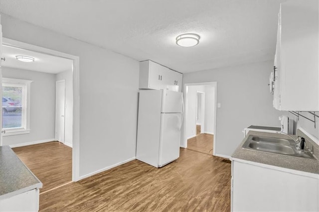 2130 E 83rd St, Kansas City, MO 64132 - kitchen featuring a sink, freestanding refrigerator, wood finished floors, and white cabinetry