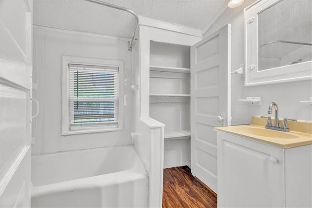 2130 E 83rd St, Kansas City, MO 64132 - bathroom with a washtub, vanity, wood finished floors, and a textured ceiling