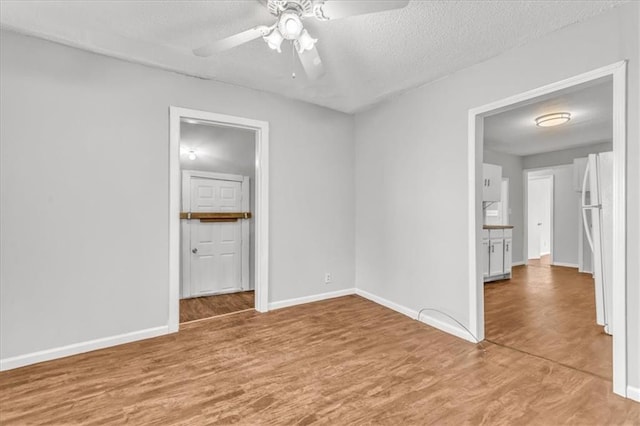 2130 E 83rd St, Kansas City, MO 64132 - spare room featuring light wood-style flooring, a textured ceiling, ceiling fan, and baseboards