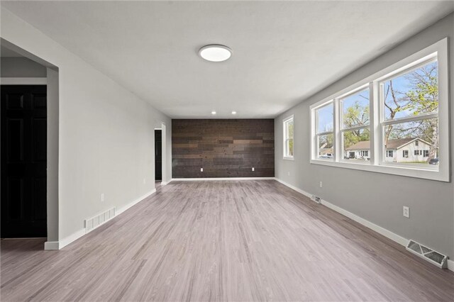 unfurnished living room with wood finished floors, baseboards, and visible vents
