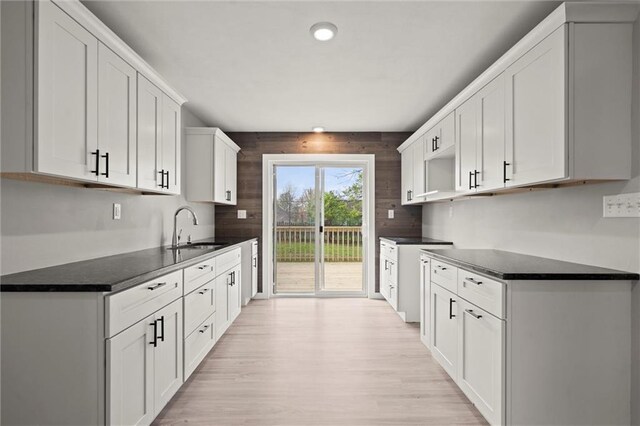 kitchen featuring a sink, dark countertops, recessed lighting, light wood finished floors, and white cabinetry