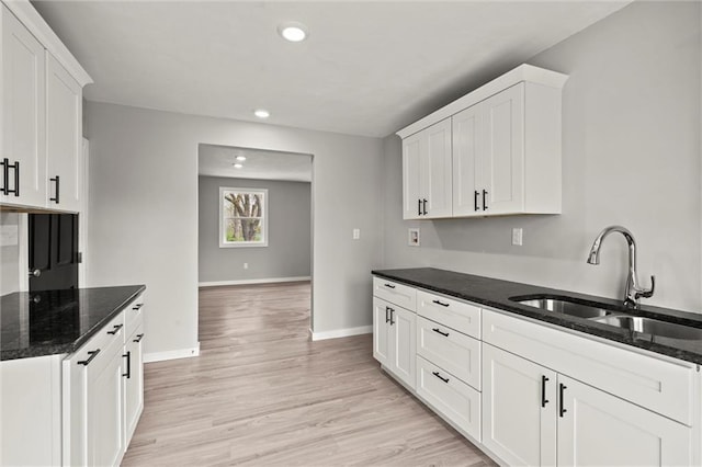 kitchen featuring white cabinets, a sink, baseboards, and recessed lighting