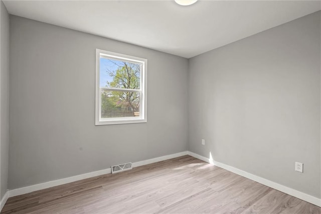 unfurnished room featuring visible vents, baseboards, and wood finished floors