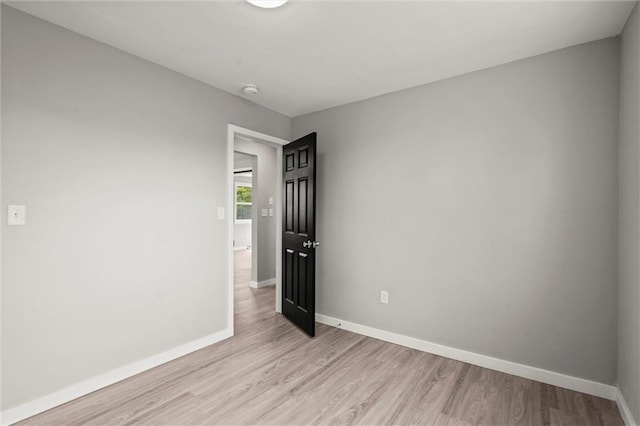 spare room featuring light wood finished floors and baseboards