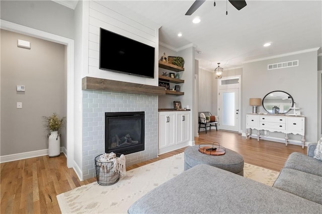 16955 W 168th Ter, Olathe, KS 66062 - living area with ornamental molding, ceiling fan, visible vents, a brick fireplace, and wood finished floors