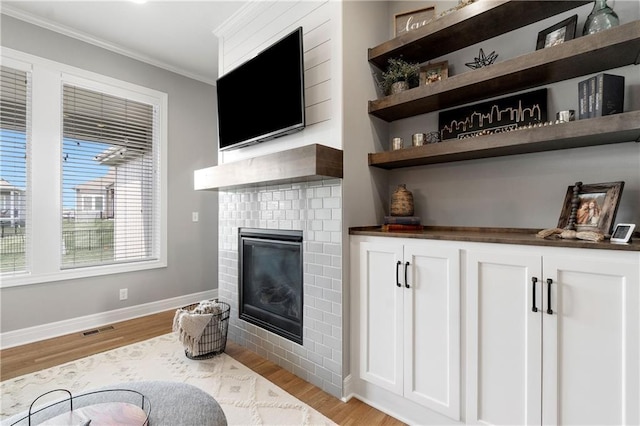 16955 W 168th Ter, Olathe, KS 66062 - bar featuring light wood-style flooring, baseboards, ornamental molding, visible vents, and a brick fireplace