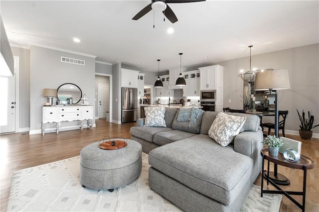 16955 W 168th Ter, Olathe, KS 66062 - living room featuring baseboards, ceiling fan with notable chandelier, light wood-type flooring, and visible vents